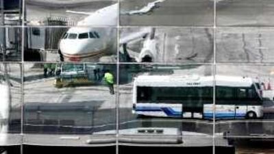 An Etihad Plane is reflected in the glass front of the new terminal 3 building at Abu Dhabi Airport.