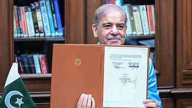 Pakistan's Prime Minister Shehbaz Sharif holds the memorandum of understanding between the US and Iran after signing it as a mediator to end the Middle East war, in Islamabad. AFP