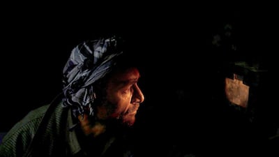 A worker peers through a hole at an oven at the cement factory.