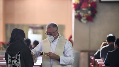 Father Stepan Lylak hands out the sacramental bread for communion during Christmas mass at St Joseph's church in Abu Dhabi. All photos by Khushnum Bhandari for The National