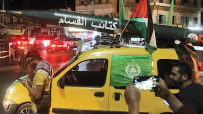 Men parade with a makeshift rocket written in Arabic, "Qassam Brigades", after the Hamas armed wing during a demonstration called by Hamas in the southern Lebanese city of Saida late on May 11, 2021. AFP