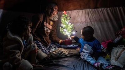 Members of Honduran migrant family Aguilar Duarte, who traveled with the Central American migrants caravan to the Mexico-US border, pose for a picture with a Christmas tree inside their tent at a temporary shelter in downtown Tijuana, Baja California state, Mexico. AFP