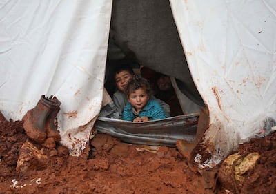 Syrian children peeking out of their tent in Cordoba camp, Idlib province. Aaref Watad / AFP