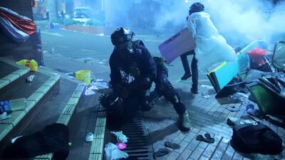 A policeman in riot gear detains a protester outside of Hong Kong Polytechnic University as police storm the campus in Hong Kong. AP