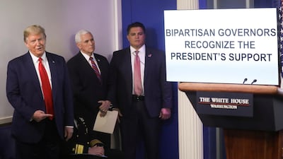 US President Donald Trump gestures towards a multimedia presentation created by the White House to defend the president's response to the coronavirus outbreak as he stands beside Vice President Mike Pence during the daily coronavirus task force briefing at the White House in Washington, US. Reuters