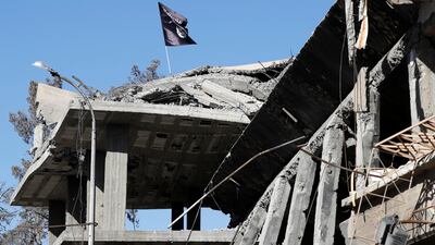 An ISIL flag is pictured above a destroyed house near the Clock Square in Raqqa. Reuters
