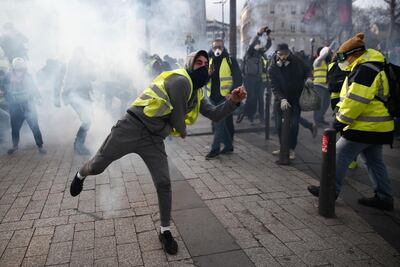 A protestor wearing a yellow vest (gilet jaune) throws a tear gas canister back at police during a protest in Paris last week. AFP