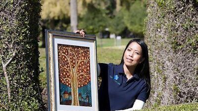 Desiree Vlekken, the founder of 4get-me-not.org, holds up a painting by the Filipino artist Jomike Tejido, titled The Memory Tree. Mike Young / The National