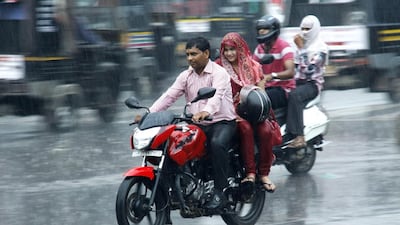 A couple riding a motorcycle brave the monsoon rains in Gurgaon, India. Manoj Kumar / Hindustan Times via Getty Images