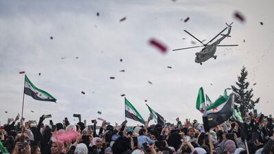 Confetti and flowers are dropped from a military helicopter onto a crowd during a celebration marking the 10th anniversary of the victory of rebel forces over Bashar Al Assad's army in Idlib, Syria. AP Photo