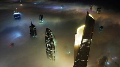 This aerial view shows Kuwait City's al-Hamra tower (R), the headquarters of The National Bank of Kuwait (C) and the al-Rayah tower (L), caught in heavy fog early on January 13, 2022. (Photo by YASSER AL-ZAYYAT / AFP)