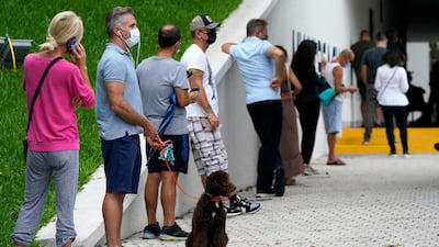 William Heuseler, second from left, waits in line to vote with his dog Ziggy, outside of an early voting site, Tuesday, October 20. AP