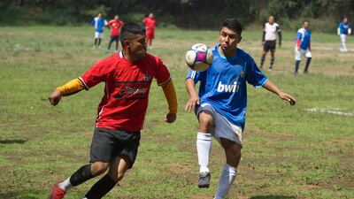 Players fight for the ball during a football match on a field at the Teoca volcano crater. AFP