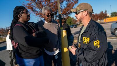 An FBI agent works to help people recover their cars from the scene. EPA