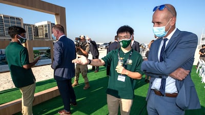 A pupil shows a guest the photo exhibition at the ceremony. Victor Besa / The National.
