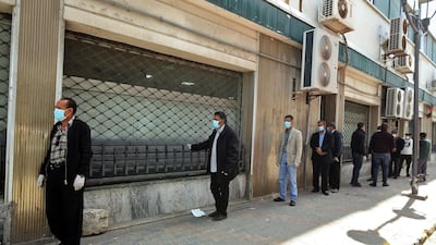 Libyans wearing protective face masks queue in front of a bank in the centre of the capital Tripoli amid the coronavirus pandemic. AFP