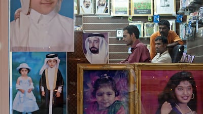 Ajman, August 7, 2011 - Ahmed Saddque moved from Sharjah to Ajman City four months ago to work in Foto Click Studios helping customers like Ramesh Rathore (tan shirt) and Gemo Yadav (orange shirt) select their photos to be printed in Ajman City. (Jeff Top???