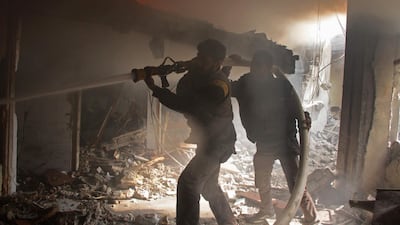 Members of the Syrian Civil Defence try to put out a fire following regime air strikes on Douma on February 7, 2018. Hamza Al Ajweh / AFP