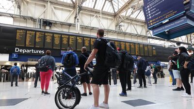 Passengers look at the departures board at Waterloo station, London, as rail workers take part in a fresh strike over jobs, pay and conditions. PA