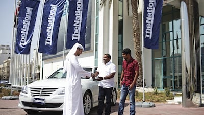 Mohammed Al Otaiba, Editor-in-Chief of The National, presents Mohammed Basheer, centre, and Ismail Palappadam with the keys to a Hyundai Genesis car. The roommates were the winners of this newspaper’s World Cup prediction competition. Lee Hoagland / The National