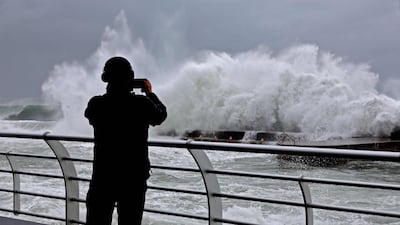 A man takes a picture of a giant wave crashing along the waterfront, Beirut. AFP
