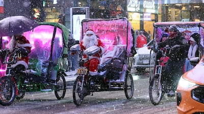 A pedicab tour guide, dressed in a Santa Claus costume, rides in Times Square during a snowfall. AFP