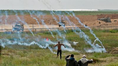 Palestinians flee as tear gas grenades begin to fall from the sky. Mahmud Hams / AFP Photo