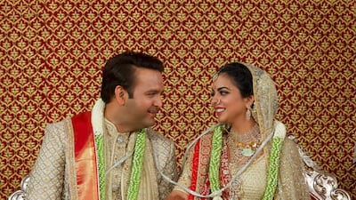 Newlyweds Isha Ambani, right, and Anand Piramal sit holding hands in Mumbai, India. AP Photo