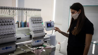 An employee of the Diamony Group operates the embroidery machine.