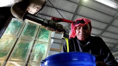 A Jordanian man pours olive oil pours in a factory.
