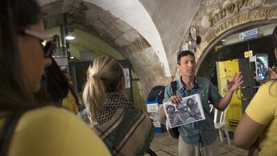 An Israeli tour guide shows one of the most iconic photographs of the 1967 Arab-Israeli war to his group of tourists from the Philippines near the entrance to the Western Wall in the Old City of Jerusalem on May 20, 2017. The black and white photograph of three Israeli paratroopers standing at the Western Wall was taken on June 7,1967 by Time Life Israeli photographer David Rubinger. Heidi Levine for The National