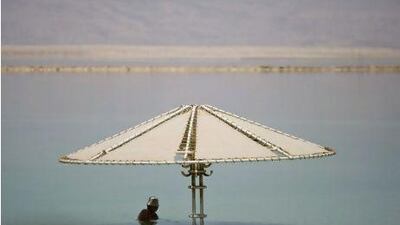 A bather wades in the waters of the Dead Sea near Neve Zohar, Israel. Israel's tourism and environmental protection ministers are endorsing a $2bn plan to chip off the salt buildup on the part of the lake that is rising and send it by conveyor belt to the northern end, which is dropping. Ariel Schalit / AP Photo