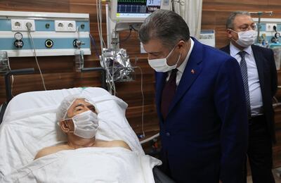 Turkey's Health Minister Fahrettin Koca speaks with Ahmet Citim, rescued from the debris of his collapsed house, in Izmir, Turkey. Turkey Health Ministry via AP