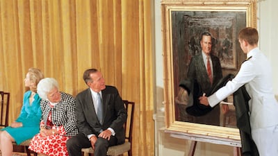 The late former president George H W Bush and his wife, the late Barbara Bush, look as his formal portrait is officially unveiled at the White House in 1995. AP