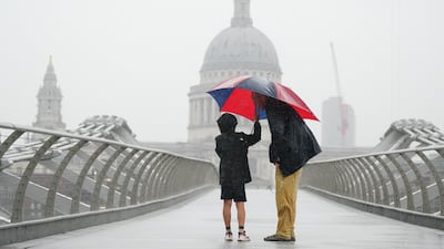 People caught in a heavy rain storm on London's Millennium Bridge last month. PA