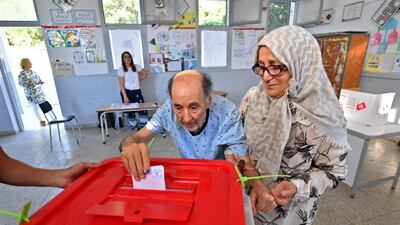 An elderly Tunisian man arrives with his wife to vote in a referendum on a draft constitution put forward by President Kais Saied, on July 25, 2022. AFP