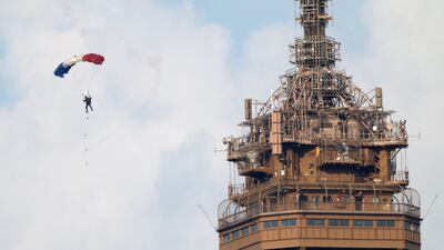 A French paratrooper parachutes past the top of the Eiffel Tower during rehearsals for the annual Bastille Day military parade in Paris. Reuters