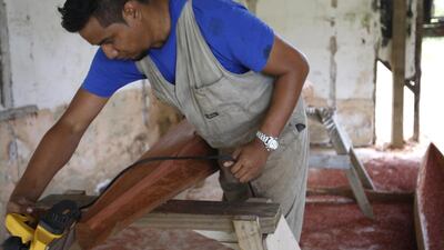 Roy Pavihi, 26, is part of a youth group that’s learning to make canoes, using traditional tools like chisels and modern ones like electric planers. He says he thinks the project is encouraging people to stay. Nick Perry/AP Photo