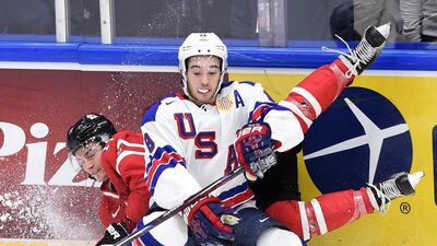 Canada’s Brendan Perlini (11) gets hit into the boards by United States’ Louie Belpedio during first period preliminary hockey action at the IIHF World Junior Championship in Helsinki, Finland. Sean Kilpatrick / The Canadian Press via AP