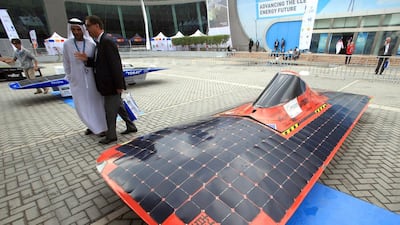 Visitors walk near solar-powered vehicles on display at the World Future Energy Summit. Yoshua Arias / EPA