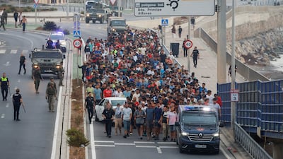 Police and soldiers in Ceuta escort a group of migrants to the border after mass crossings from Morocco into Spanish territory on August 1. Reuters