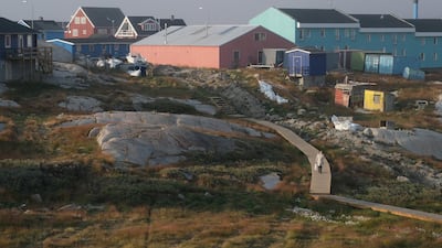 A woman walks on a boarded path in the town center in Ilulissat. Getty Images