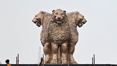 A worker walks past the newly inaugurated 'National Emblem' on the roof of the new Indian Parliament building in New Delhi. AFP