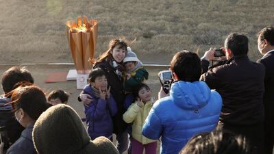 A family takes a selfie with the Olympic flame on a cauldron displayed at Ishinomaki Minamihama Tsunami Recovery Memorial Park. EPA