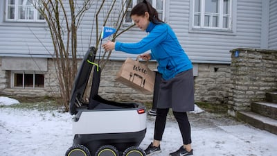 A woman takes delivery of food from a six-wheeled robot by Starship Technologies from restaurant in Tallinn, Estonia. Raigo Pajula/AFP