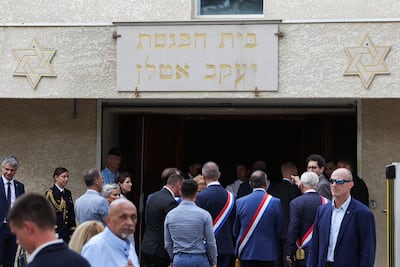 People stand by the entrance to the city synagogue in La Grande-Motte, in southern France, after cars were set on fire in front of it. Reuters