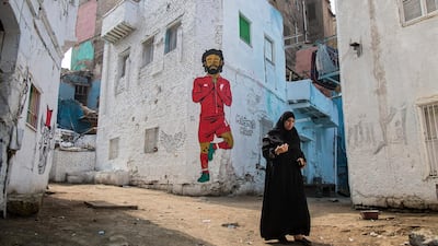 A woman walks past a mural depicting Liverpool's Egyptian striker Mohamed Salah in Cairo. EPA