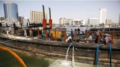 Recovery crew pump water from the burnt hull of the dhow.