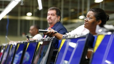 A worker uses a remote control to check 32-inch television sets before they are repackaged at Element Electronics in Winnsboro, South Carolina. Element's plant in South Carolina has six assembly lines making 32- and 40-inch TVs that are now available in all of Walmart’s more than 4,000 US stores. Chris Keane / Reuters