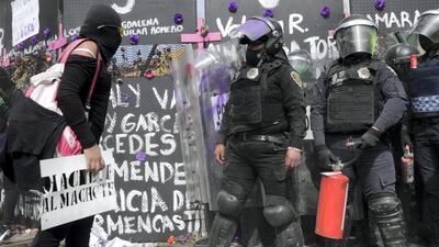Police officers stand guard as women protest in front of fences placed outside the National Palace on International Women's Day in Mexico City, Mexico. Reuters